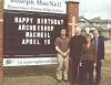 Archbishop MacNeil standing by the announcement board at Archbishop Joseph MacNeil school on his birthday