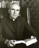 Archbishop MacNeil sitting with a book in his office