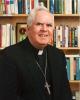 Archbishop MacNeil in front of bookcase in his office